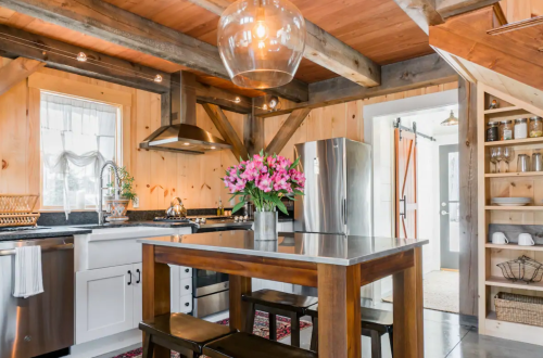 Cozy kitchen with wooden beams, modern appliances, a dining table, and a vase of flowers on the table.
