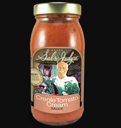 A jar of Sal & Judy's Creole Tomato Cream Sauce featuring a vibrant red sauce and a smiling chef on the label.