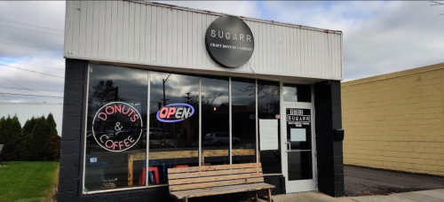 Exterior of Sugarr, a craft donut and coffee shop, featuring a "Donuts & Coffee" sign and an "Open" neon sign.