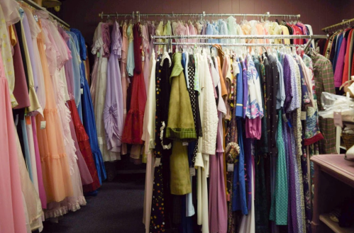 A clothing rack filled with a variety of colorful dresses and garments in a boutique setting.