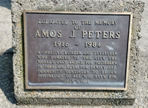 Plaque dedicated to Amos J. Peters, honoring his contributions and the world's only squirrel bridge he donated in 1963.