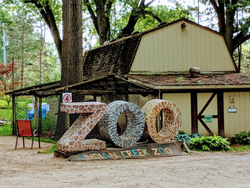 Sign at Indian Creek Zoo featuring large, decorative letters spelling "ZOO" in a natural setting.