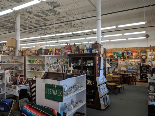 A spacious antique store filled with various vintage items, shelves, and displays under a patterned ceiling.