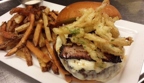 A juicy burger topped with crispy fried onions, served with a side of golden French fries.