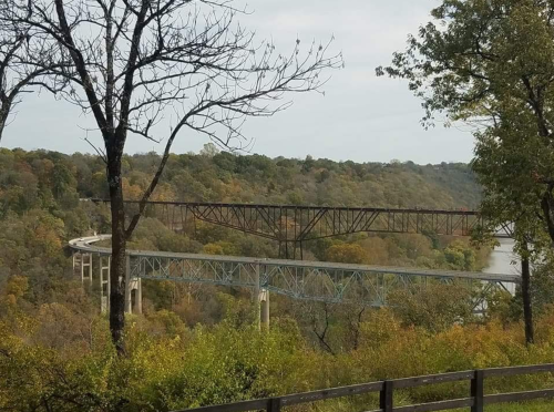 A view of two bridges spanning a river, surrounded by trees with autumn foliage.