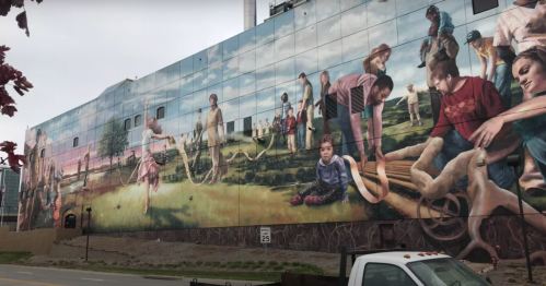 A colorful mural depicting people engaged in various activities outdoors, set against a scenic background.