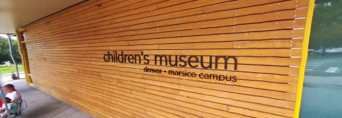 Exterior of the Children's Museum, featuring a wooden wall with the museum's name and location in Denver.