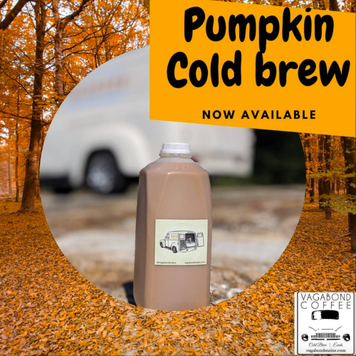 A jug of pumpkin cold brew coffee in an autumn setting with orange leaves and a blurred background.