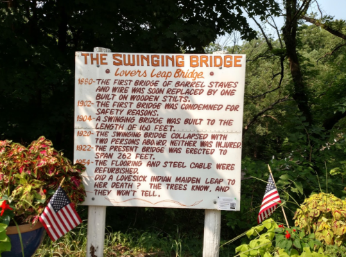 Sign detailing the history of the Swinging Bridge, including dates and events related to its construction and incidents.