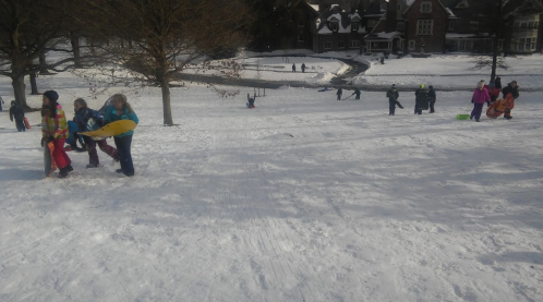 Children playing in the snow, sledding and enjoying winter activities on a snowy hill.