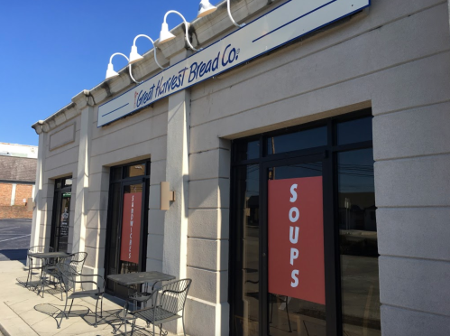 Exterior of Great Harvest Bread Co. featuring a sign and windows displaying "Soups" and "Sandwiches."