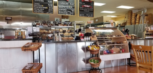 A cozy café interior featuring a display case with baked goods, a menu board, and a seating area.
