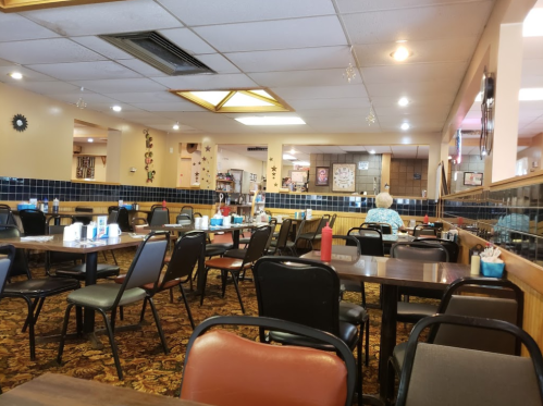 A spacious diner with empty tables, colorful decor, and a lone customer sitting in the background.