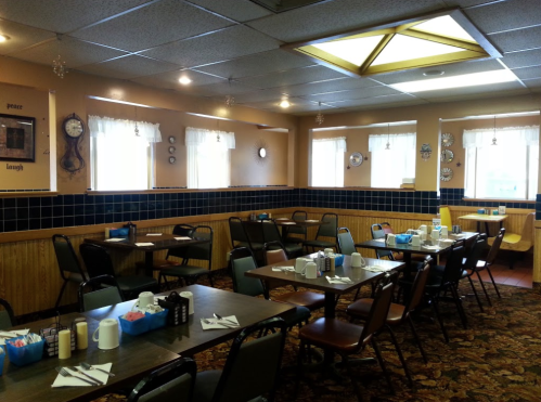 Cozy diner interior with tables set for dining, featuring colorful decor and large windows letting in natural light.