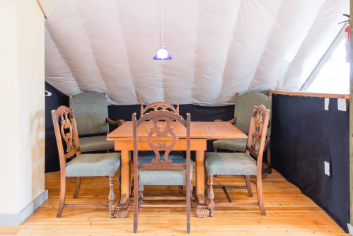 A cozy attic dining area with a wooden table and four chairs under a sloped ceiling.