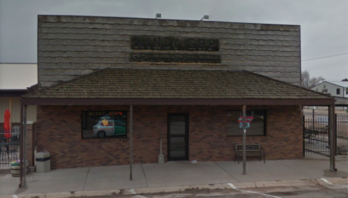 Exterior of a rustic building with a shingled roof, featuring a sign that reads "Kandy Kapp Grill & Saloon."