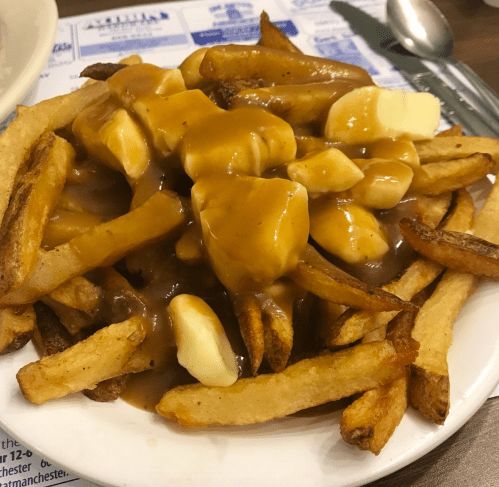 A plate of fries topped with gravy and cheese curds, a classic dish known as poutine.