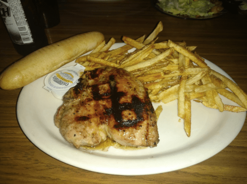Grilled chicken breast with fries and a breadstick, served on a white plate.