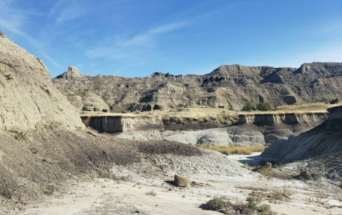 A rugged landscape with layered hills and a clear blue sky, showcasing the natural beauty of a dry, arid region.