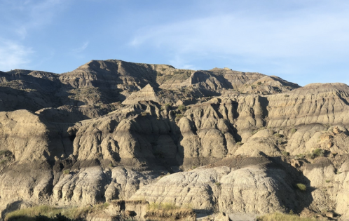 A rugged landscape of layered hills and rock formations under a clear blue sky.