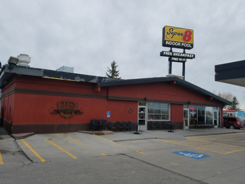 Exterior of a Super 8 motel with an indoor pool sign, featuring a BBQ restaurant and parking spaces.