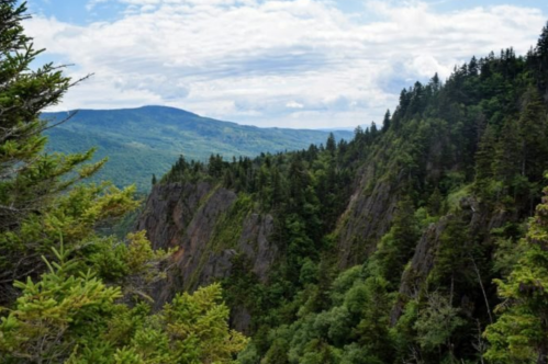 A scenic view of mountains and lush greenery under a partly cloudy sky.