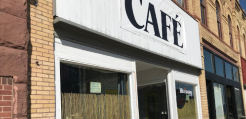 A café storefront with a large sign reading "CAFÉ" and windows displaying a welcoming interior.