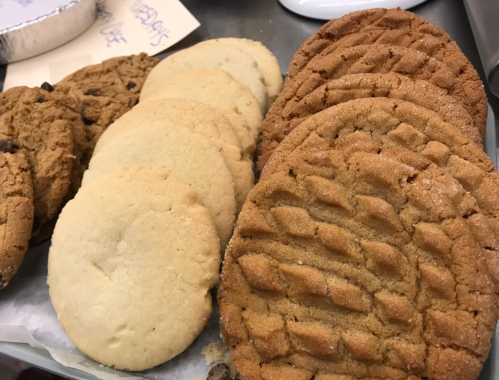A tray of assorted cookies, including peanut butter and chocolate chip, arranged neatly on parchment paper.