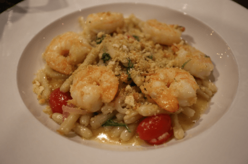 A plate of pasta topped with shrimp, cherry tomatoes, and a sprinkle of breadcrumbs in a light sauce.