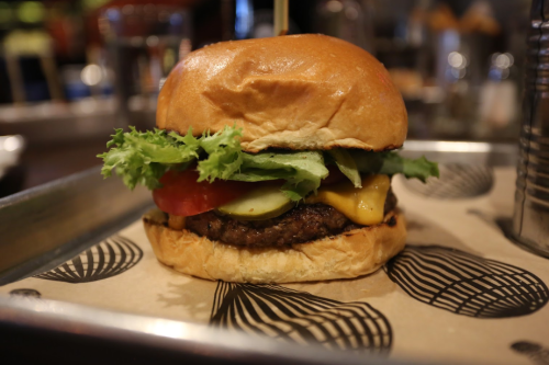 A juicy cheeseburger with lettuce, tomato, pickles, and a soft bun, served on a patterned tray.