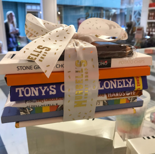 A stack of colorful books and snacks tied with a ribbon, displayed in a shop.