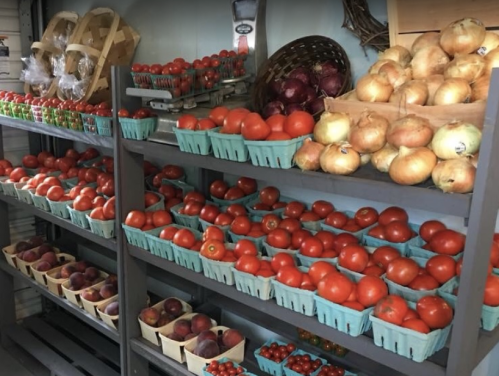 Shelves filled with various fresh produce, including tomatoes, onions, and apples in baskets.
