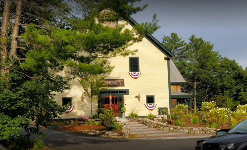 A charming yellow barn-style building surrounded by greenery and decorated with patriotic bunting.