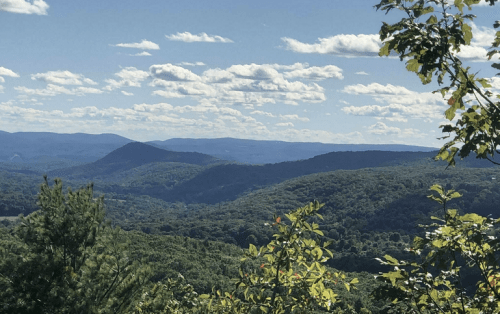 A scenic view of rolling green hills under a blue sky with fluffy white clouds.