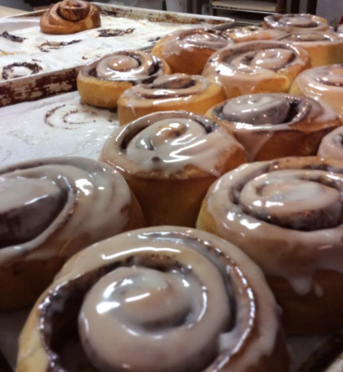 Freshly baked cinnamon rolls with creamy icing, arranged on a baking tray.