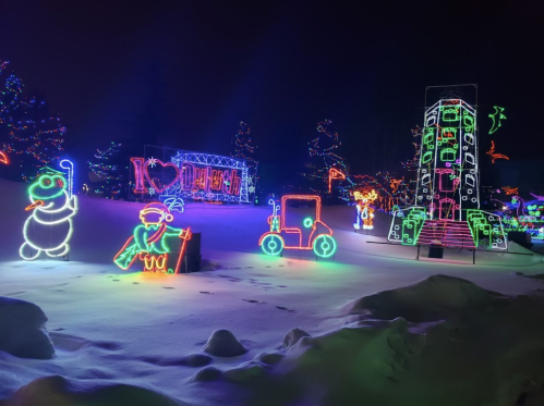 Colorful holiday lights illuminate a snowy landscape, featuring a snowman, a rocket, and festive decorations.