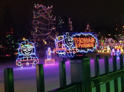 Colorful holiday lights display featuring Thomas the Tank Engine and friends, set against a dark night sky.
