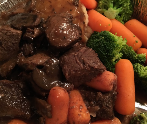 A close-up of a hearty meal featuring tender beef, carrots, broccoli, and a savory sauce.
