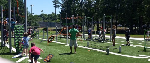 A vibrant playground filled with children playing on various climbing structures and equipment on a sunny day.