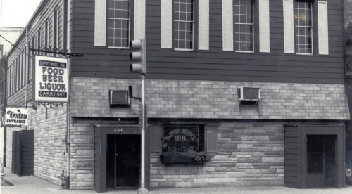 Historic building exterior featuring a liquor store and tavern entrance, with a vintage sign and traffic light.