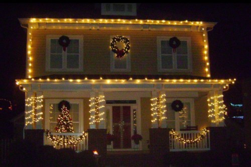 A beautifully decorated house with warm white lights, wreaths, and a Christmas tree, creating a festive holiday atmosphere.