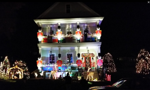 A beautifully decorated house at night, featuring colorful lights, nutcracker figures, and festive holiday decorations.