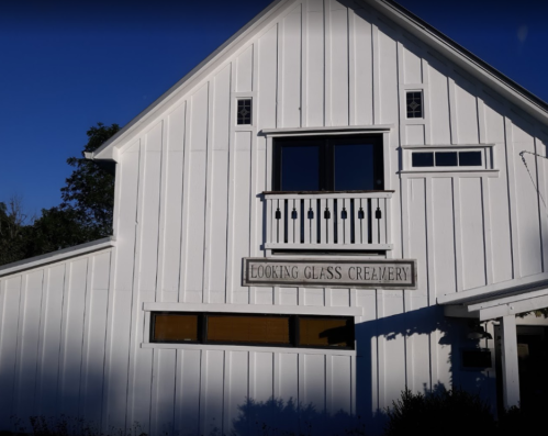 A white wooden building with a sign reading "Looking Glass Creamery" and large windows.