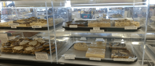 A display case filled with various fudge flavors, including chocolate, peanut butter, and butter pecan.