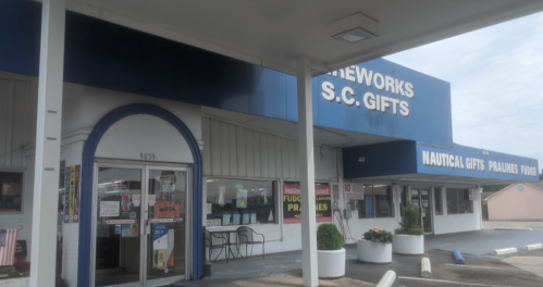 Storefront of S.C. Gifts featuring fireworks and nautical items, with a blue awning and signage.