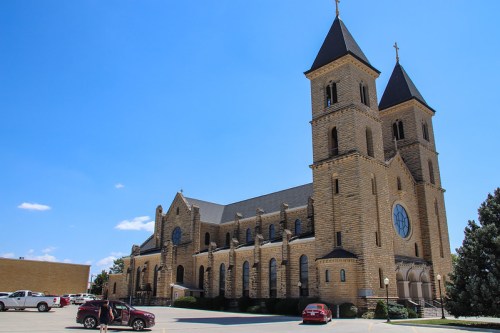 A large stone church with two tall towers and a round window, set against a clear blue sky.