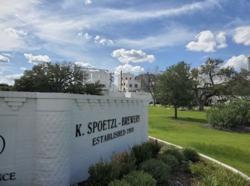 Sign for K. Spoetzl Brewery, established in 1909, with a green lawn and cloudy sky in the background.