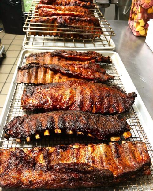A tray of perfectly cooked, smoky barbecue ribs arranged on a cooling rack, showcasing a rich, caramelized glaze.