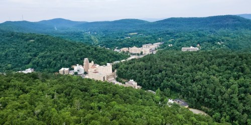 Aerial view of a lush green landscape with a small town nestled among the hills and mountains in the background.