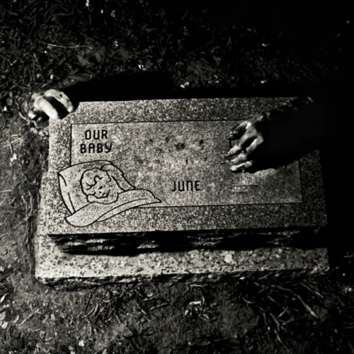 A gravestone with the inscription "Our Baby June," surrounded by dark shadows and hands reaching out.